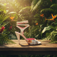 A single high-heeled sandal with a cream-colored leather upper and heel, decorated with a floral print on the toe strap. It features multiple thin wrap-around ankle straps with small gold-tone buckles and a vibrant pink insole.